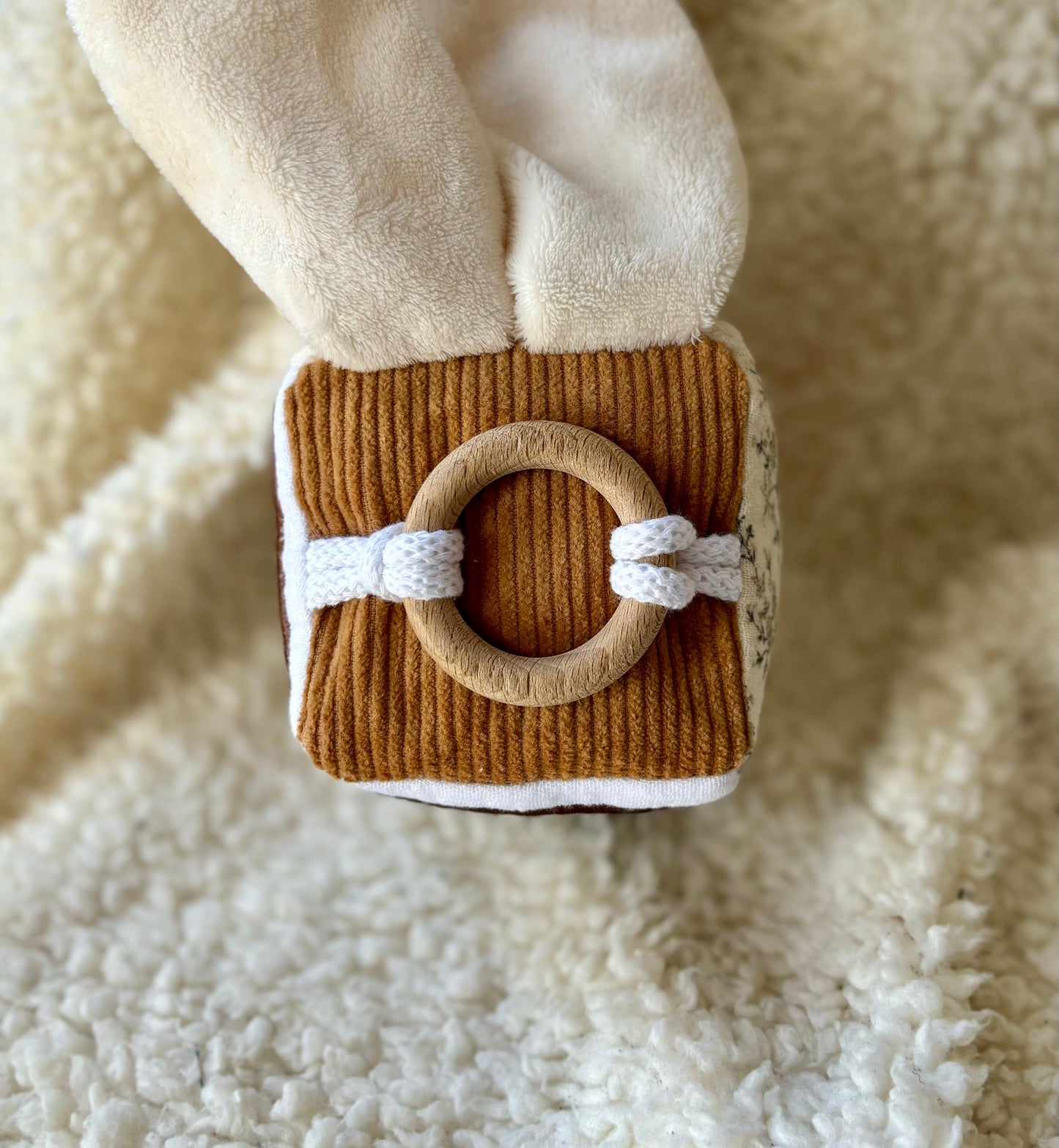 face du cube d'éveil les lapidoux ! avec un anneaux en bois de hêtres fixé sur un velours côtelé 